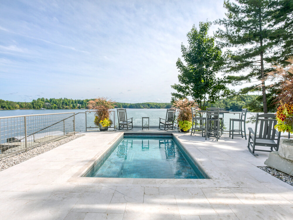 A hot tub set into the stone terrace at the water&rsquo;s edge at Lakemore, looking out over Arbutus Lake.