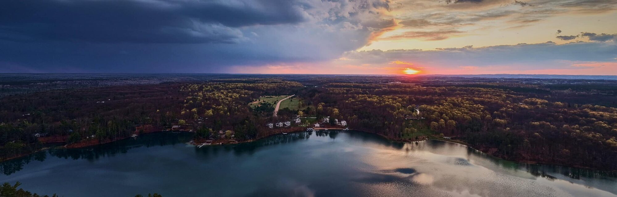 Arbutus Lake from the air at sunset, the shoreline houses small against the water.