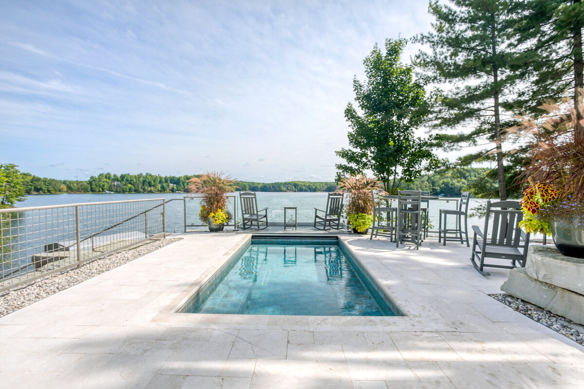 A hot tub set into the stone terrace at the water&rsquo;s edge, looking out over Arbutus Lake.