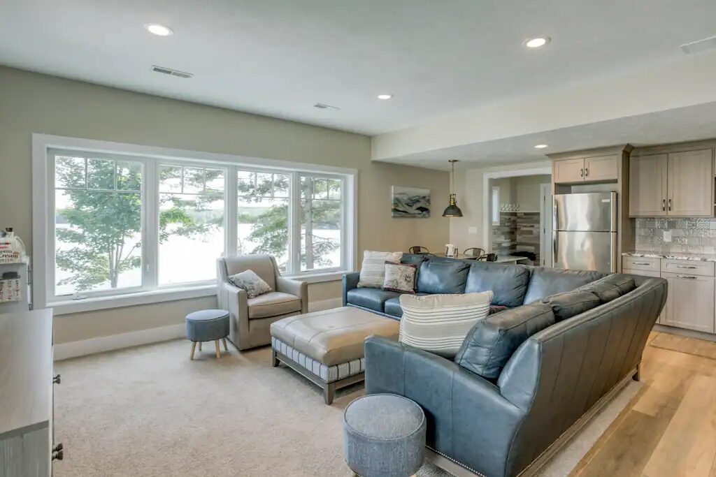 The lower-level living room with a large sectional sofa facing windows onto the lake.
