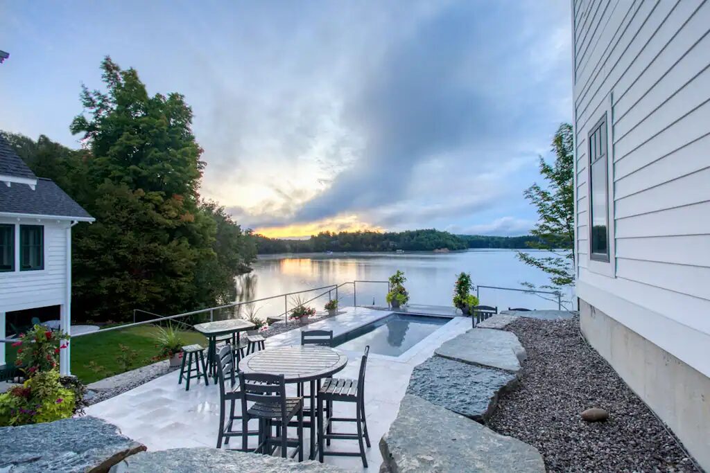 The lakeside patio of a Lakemore house at sunset, with a table and chairs looking out over Arbutus Lake.