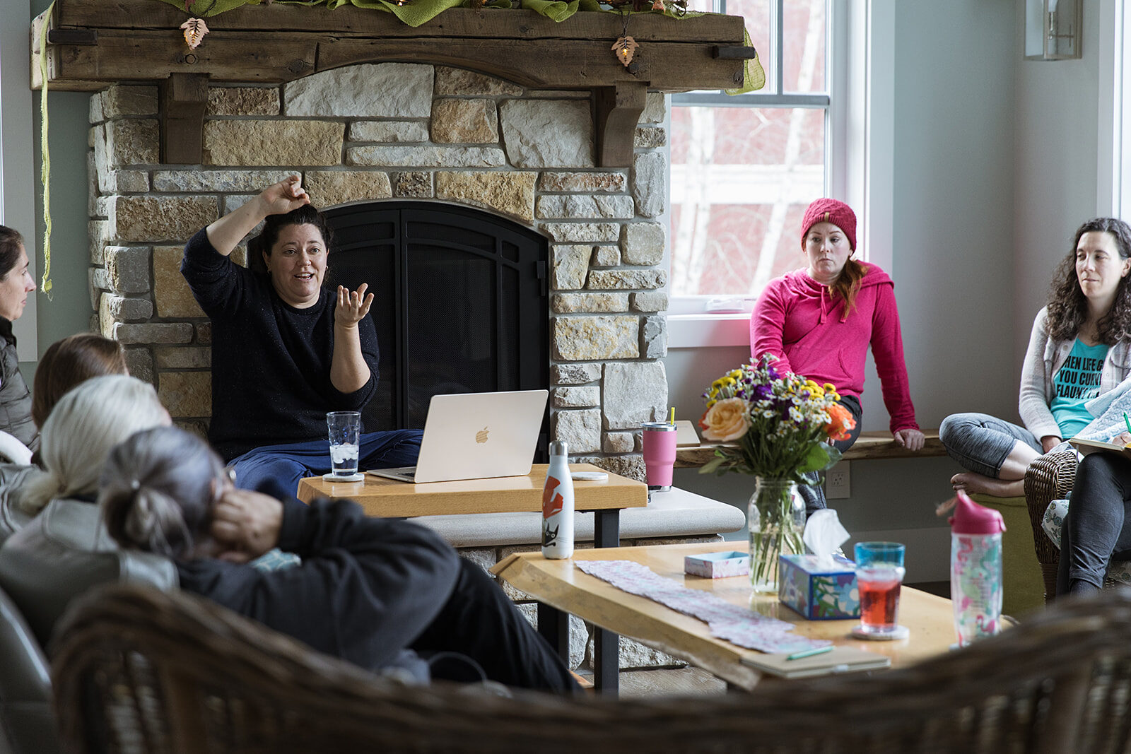 A group seated around a living room with a stone fireplace, laptops open, mid-session.